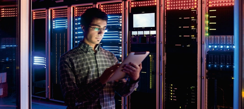 Interior moderno de una sala de servidores en un centro de datos. Ingeniero informático en acción configurando servidores.